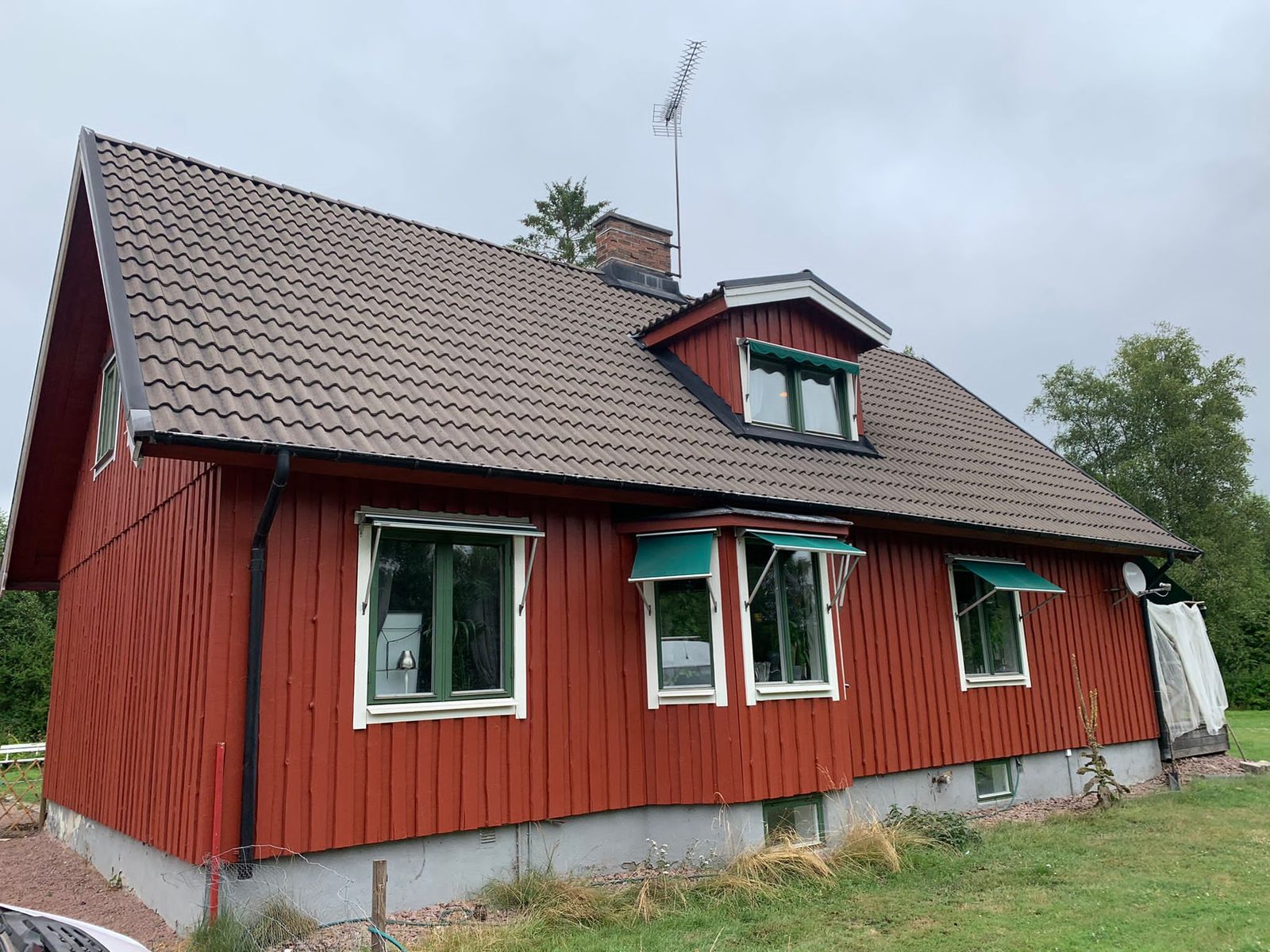 Röd villa med renoverat tak i varm kulör